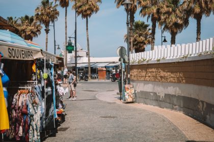 Mercado de souvenirs com visitantes e palmeiras em uma rua de Málaga, na Espanha.