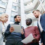 Equipe multicultural reunida em um escritório moderno, analisando documentos e um tablet durante uma reunião de trabalho